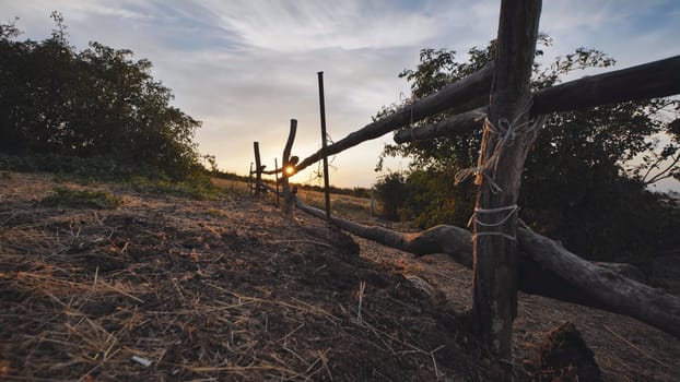 Rustic wooden fence dividing fields in the Crimean countryside, bathed in the warm glow of the setting sun