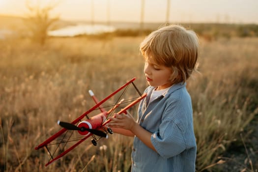 Smiling curious 5 years old preschool child boy plays with craft wooden retro styled airplane toy, discovering future profession interest, dreamer kid flying, traveling. High quality photo