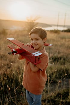Smiling curious 5 years old preschool child boy plays with craft wooden retro styled airplane toy, discovering future profession interest, dreamer kid flying, traveling. High quality photo