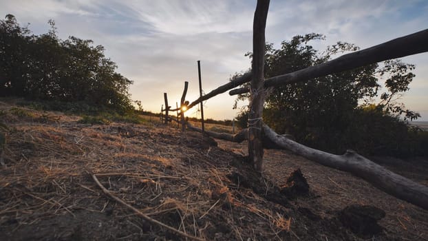 Rustic wooden fence dividing fields in the countryside, creating a picturesque scene at sunset
