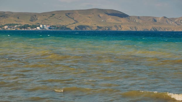 Small waves are rolling on the Black Sea near Koktebel, Crimea, with the extinct volcano Kara Dag in the background