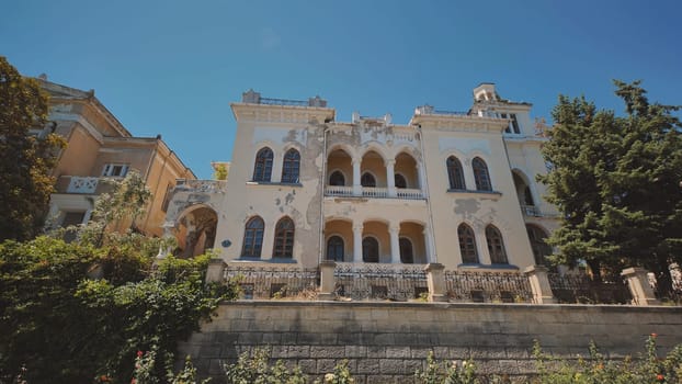 Old abandoned mansion in Crimea peninsula with decaying facade and overgrown vegetation, showing signs of neglect and disrepair