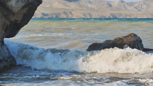 Waves breaking on the rocky shore with Crimean mountains in the background