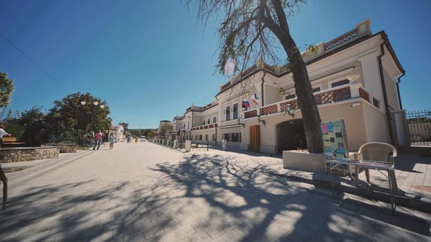 Tourists walking near the embankment in Koktebel, Crimea, Russia, on a sunny summer day