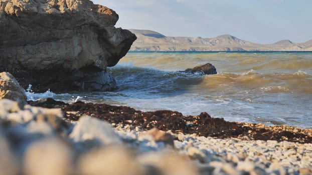 Scenic view of waves crashing on a rocky beach in Crimea, with mountains visible in the distance