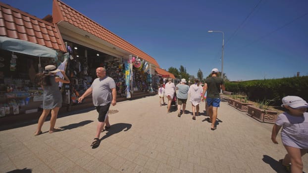 Tourists carrying inflatable rings walking past souvenir shops on a sunny summer day in crimea, a popular vacation destination on the black sea coast
