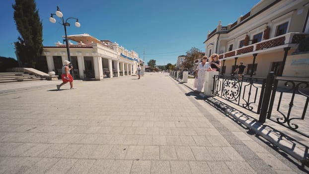 People enjoying a walk along the paved promenade in Gurzuf, Crimea, on a sunny summer day