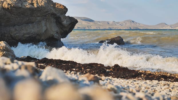 Seascape showing waves crashing on a rocky beach in Crimea, with mountains visible in the distance