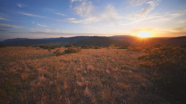 Golden hour illuminating Crimean landscape with dry meadow in the foreground and layers of mountains in the background