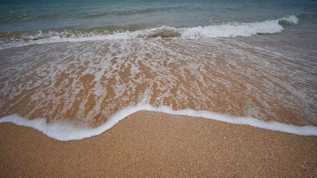 Sea wave gently covering golden sand on a beach in Crimea