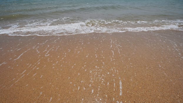 Gentle waves washing over golden sand on a Crimean beach, creating a serene coastal scene