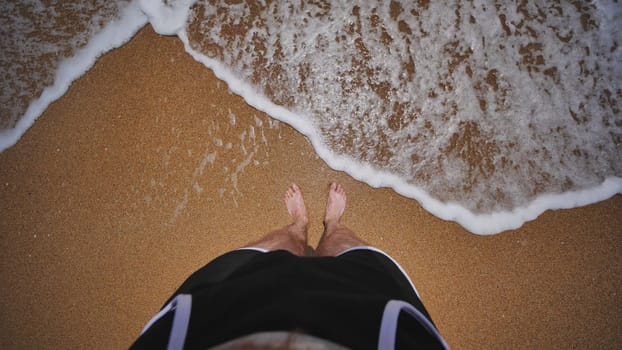Tourist standing on Crimean beach with sea waves washing over feet