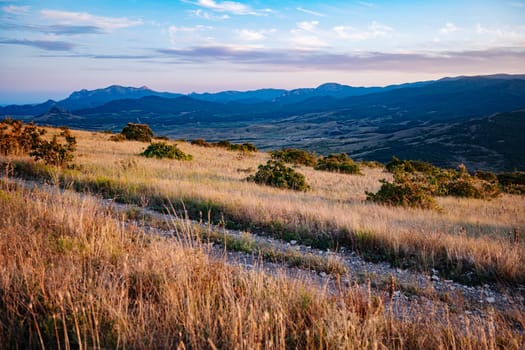 Golden hour sunlight illuminating vast Crimean landscape with mountains and meadows