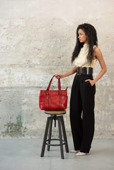 A fashionable model confidently showcasing a modern outfit while sporting a vibrant red bag accessory