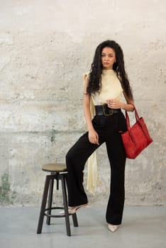 A fashionable model confidently showcasing a modern outfit while sporting a vibrant red bag accessory