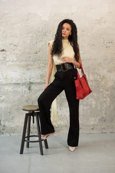 A fashionable model confidently showcasing a modern outfit while sporting a vibrant red bag accessory