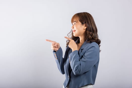 Asian happy portrait beautiful cute young businesswoman standing makes gesture two fingers point upwards above presenting product something, studio shot isolated on white background with copy space