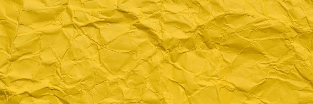 A textured yellow crumpled paper background with natural creases and folds. Ideal for design projects, digital graphics, or creative presentations requiring a vibrant, Long banner