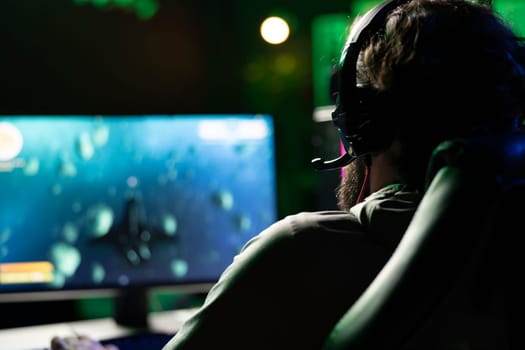 Gamer using headset and computer to play spaceship flying singleplayer game with overlay HUD showing health, fuel, ammo bars and minimap. Man playing space exploration simulation game, wearing headset