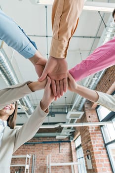 Colleagues come together in a bright office environment, placing their hands in a show of teamwork and collaboration during a productive meeting. Generative AI.