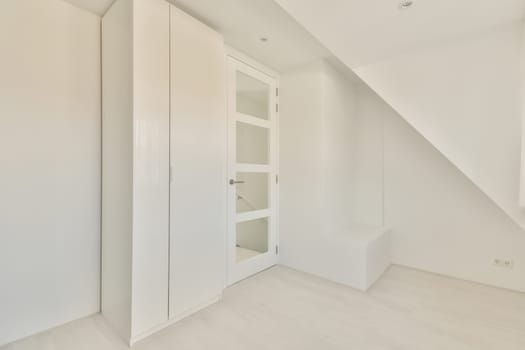 an empty room with white walls and wood flooring, the door is open to reveal a large closet space