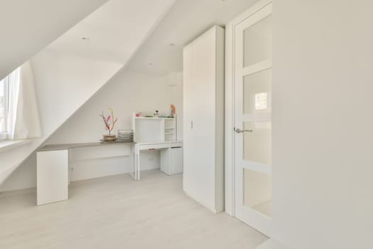a bedroom with white walls and wooden flooring, an open door to the left is a small desk on the right side