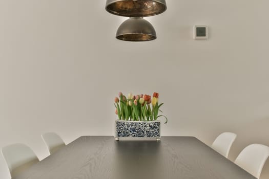 a dining room with white chairs and a wooden table in front of a large pendant light hanging above the table