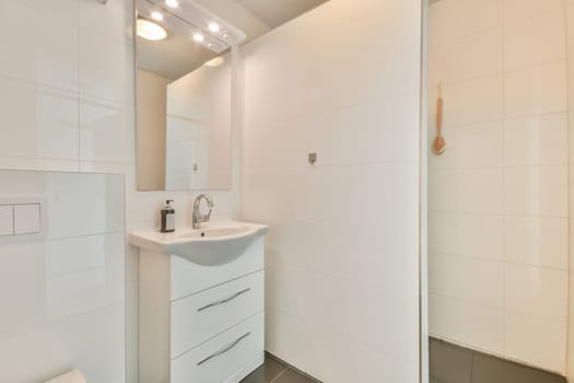 a bathroom with white walls and tile flooring, including a sink in the corner between the shower stall door