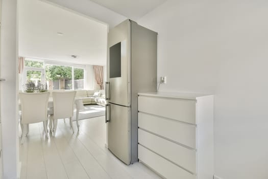 a kitchen and dining area in a modern apartment with white walls, wood flooring and an open door leading to the living room