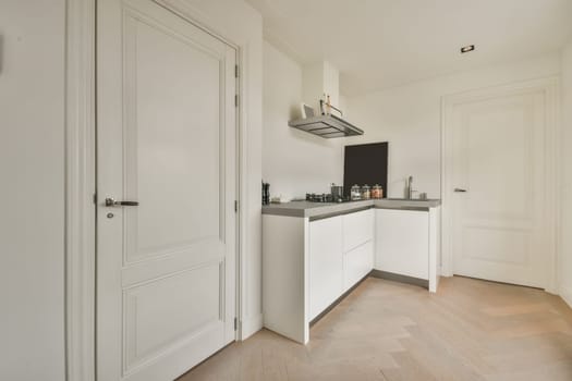a kitchen with white cabinets and black appliances on the wall above it is an open door that leads to another room