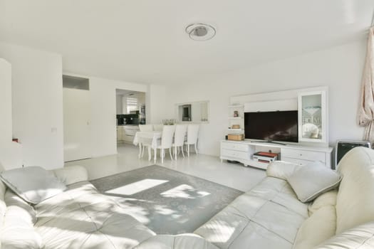 a living room with white couches and television on the wall in front of the sofa is an entertainment center