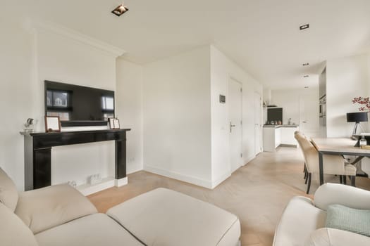 a living room with white furniture and a flat screen tv mounted on the wall above the fireplace in this apartment