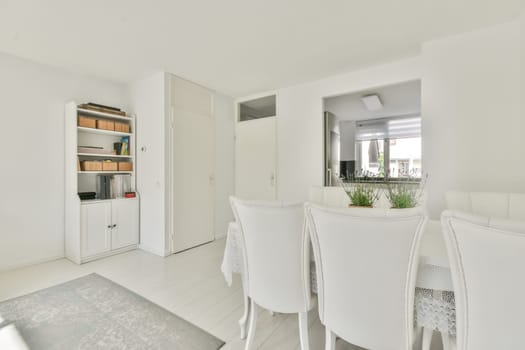 a dining room with white furniture and an open door that leads to the living area there is a large window