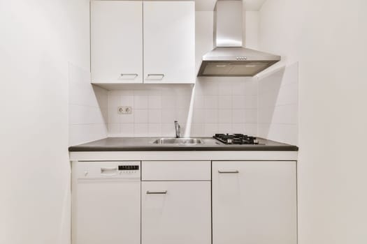 a small kitchen with white cabinets and black counter tops on the wall above it is a stove, sink and dishwasher