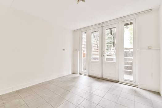 an empty living room with white walls and floor tiles on the floor, there is a sliding glass door that leads to a patio