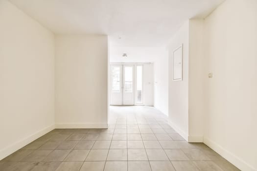 an empty room with white walls and wood flooring on the right, there is a door leading to another room