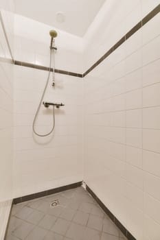 a bathroom with tile flooring and white tiles on the walls, including a shower head mounted to the wall