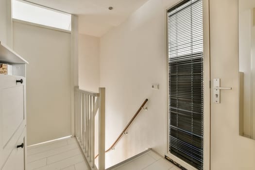 a hallway with white walls and black blinds on the window sies in front of the door to the room