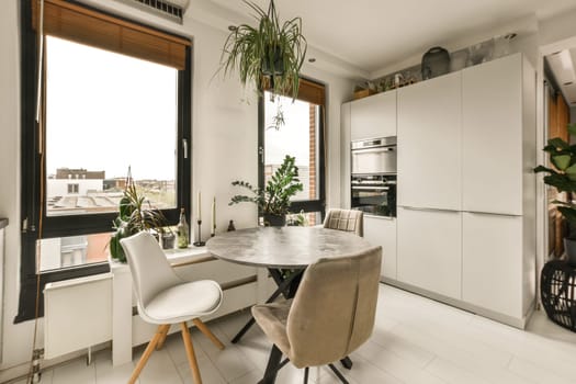 a kitchen and dining area in a house with white tiles on the floor, walls, windows, and doors