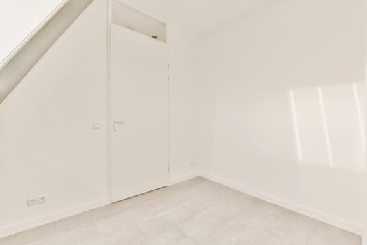 an empty room with white walls and flooring, there is a door in the corner that leads to another room