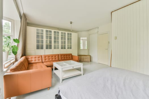 a living room with an orange couch and white bed in the photo is taken from the front door to the bedroom