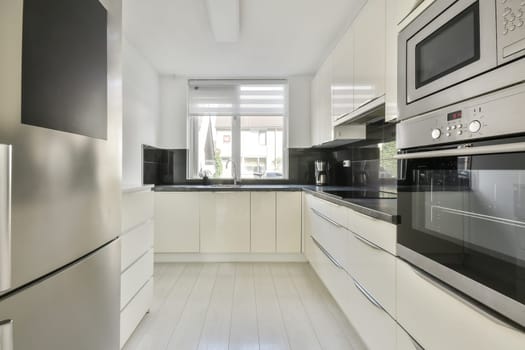 a modern kitchen with white cabinets and black countertops on the wall, along with stainless appliances in the room