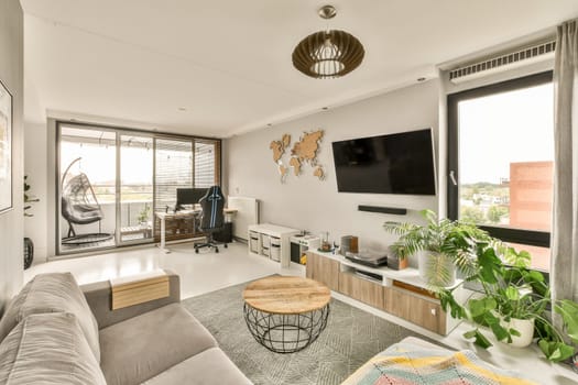 a living room with couch, tv and plants in the corners on the right hand side of the room