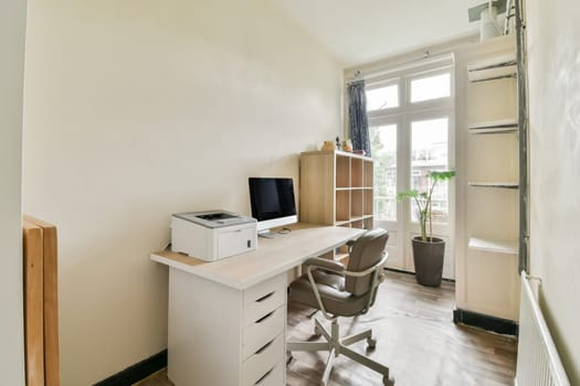 a room with a desk, chair and computer on the wall next to it is a window that looks out onto an outside view