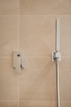 a shower head and hand rail in a tiled bathroom photo taken from the side, with focus to the wall stock photo
