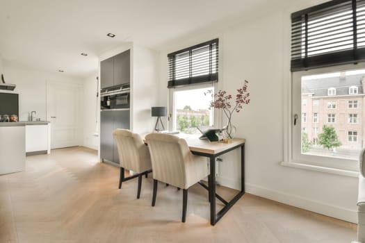 a kitchen and dining area in a modern apartment with white walls, hardwood flooring and large windows looking out onto the street