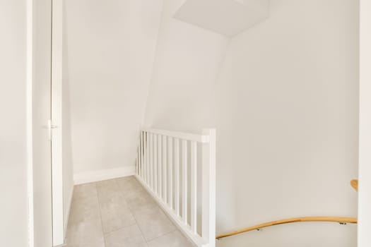 an empty room with white walls and wood railings on either side, there is a staircase leading up to the second floor