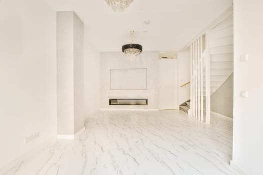 an empty living room with marble flooring and white walls there is a chandel light hanging from the ceiling