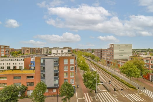 a city with buildings and train tracks in the middle part of the photo is taken from an overpass bridge