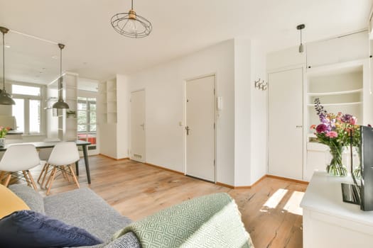 a living room with white walls and wood flooring in the center of the room is an open kitchen area
